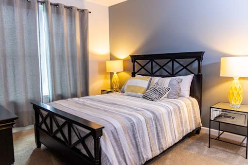 A bedroom with a bed, nightstand, and lamp.