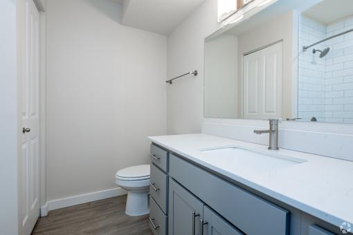 A white toilet sits in a bathroom with a white sink and a white door.
