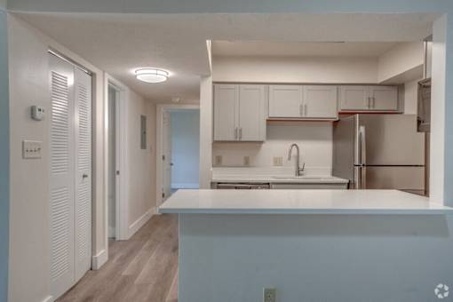 an empty kitchen with white cabinets and a white counter top