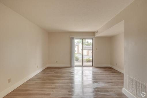 an empty living room with a sliding glass door to a patio