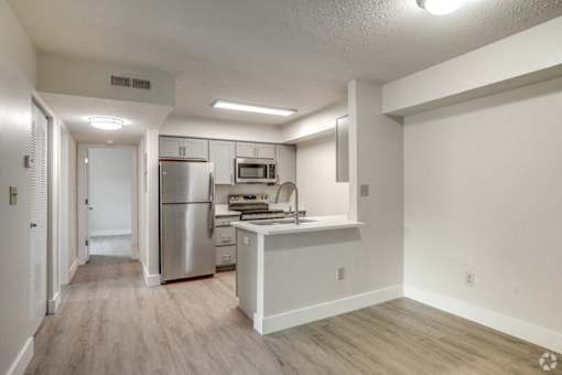 an empty kitchen with stainless steel appliances and white cabinets