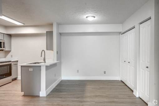 an empty kitchen and living room with white walls and wood floors
