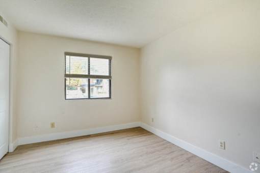 an empty living room with white walls and a window