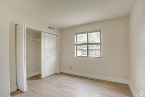 an empty bedroom with a closet and a window