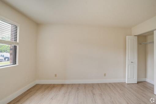 the living room of an empty house with wood flooring and a window