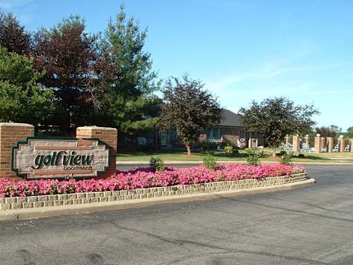 the sign for the golf view neighborhood in front of a flower garden
