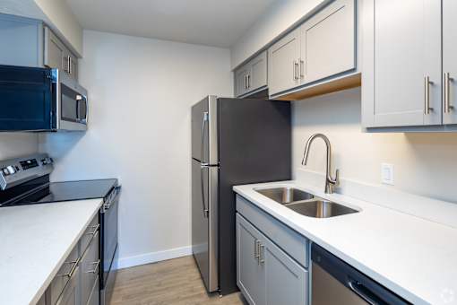 A kitchen with a black refrigerator and stainless steel appliances.