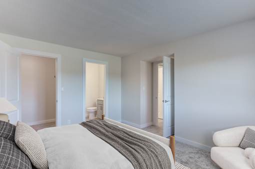 A bedroom with a bed, chair, and two doors.