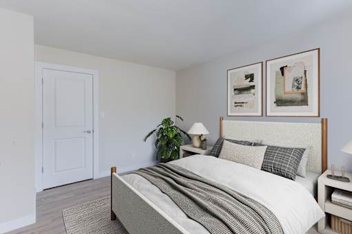 A bedroom with a bed, nightstands, and a plant.