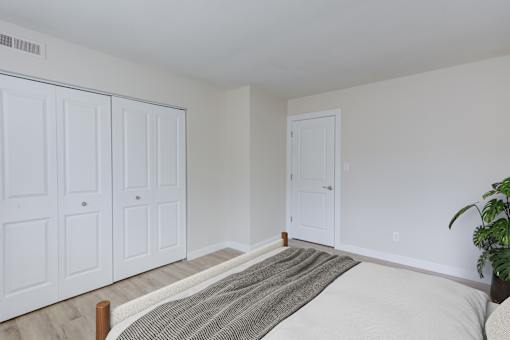 A bedroom with a bed, a plant, and a wardrobe.