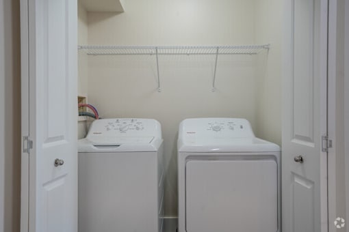 two white washing machines in a white laundry room
