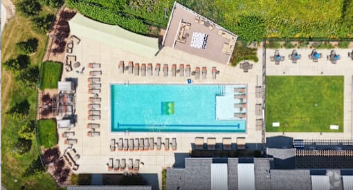 An aerial view of a pool surrounded by lounge chairs and a grassy area.
