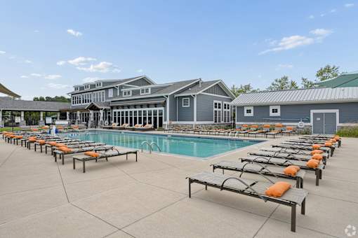 A large swimming pool with sun loungers and a building in the background.