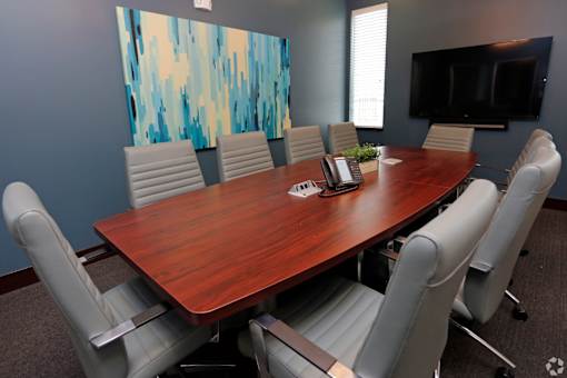 A conference room with a large table and chairs.