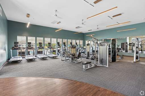 A gym with a variety of equipment including treadmills, weights, and exercise machines.