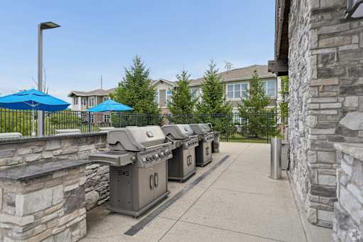A row of outdoor grills are lined up on a patio.