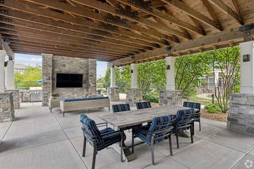 A patio with a table and chairs and a stone fireplace.