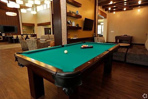 A pool table with a green cloth and white ball in the middle of it.