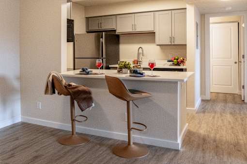 A kitchen with a white counter and two brown barstools.