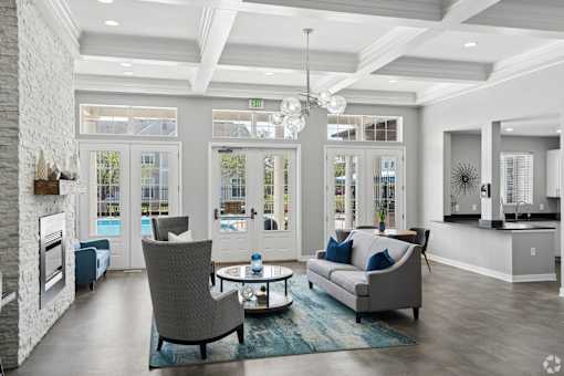 A modern living room with a grey sofa, a grey armchair, a coffee table, and a fireplace.