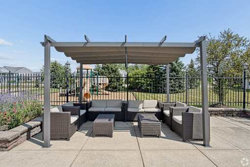 A patio with a grey sofa and a grey table under a grey canopy.