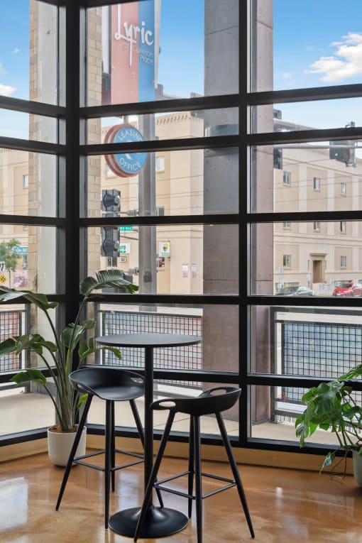 a table and two chairs in front of a window with a view of a building
