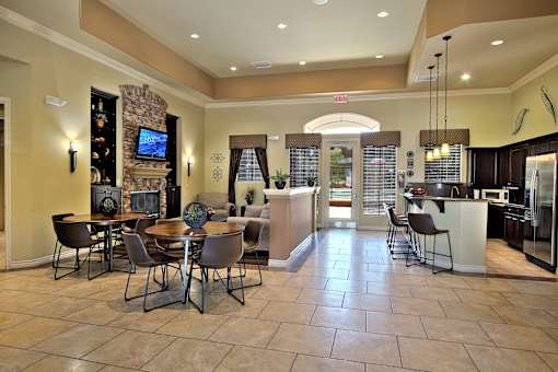 A spacious living room with a stone fireplace and a dining table set up.