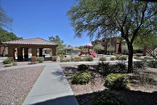 A playground with a slide is surrounded by trees and bushes.