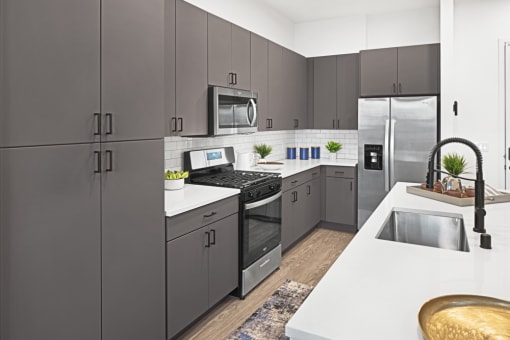 a modern kitchen with stainless steel appliances and white counter tops at Aura Vegas Apartments, Las Vegas, NV 89103