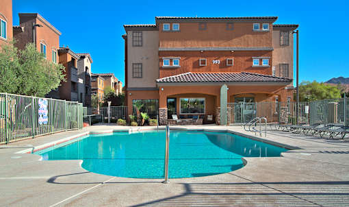 A large brown building with a pool in front.