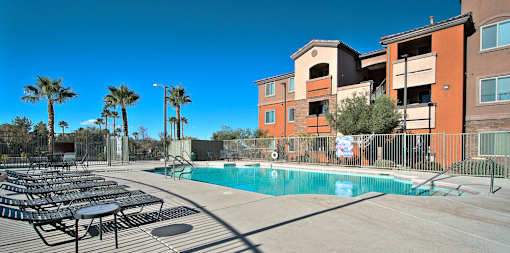 A pool surrounded by chairs and palm trees.