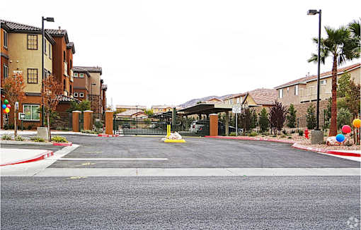 A street view of a residential area with houses on both sides and a gated entrance in the middle.