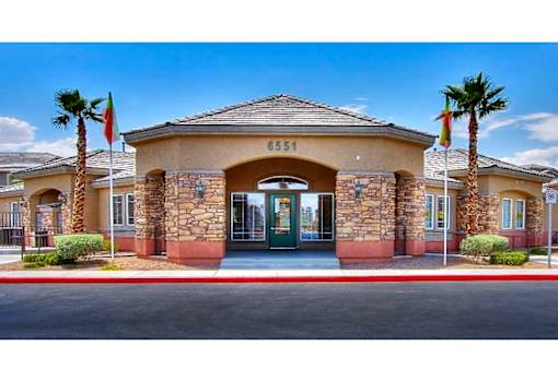 The image shows a building with the number 6551 on it, surrounded by palm trees and a clear sky.