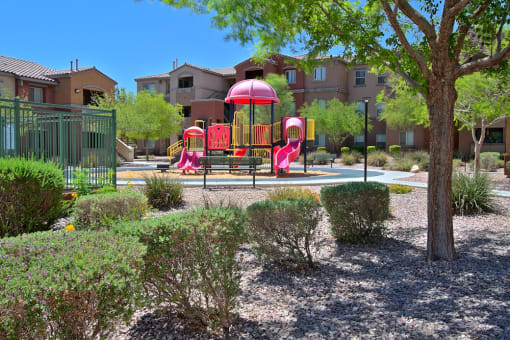 a playground with a red and yellow swing set in a park