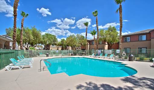 A swimming pool surrounded by palm trees and lounge chairs.
