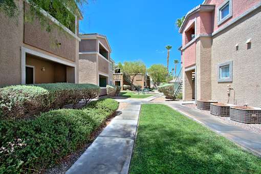 A sunny day in a residential area with apartment buildings and a sidewalk.