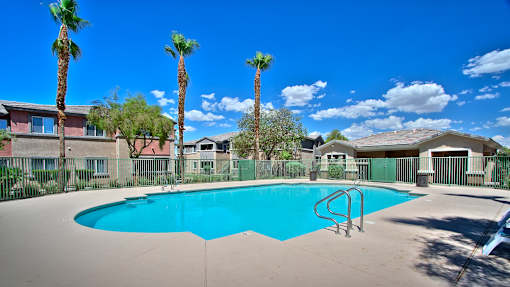 A swimming pool surrounded by palm trees and apartment buildings.