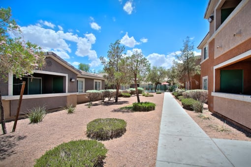 a courtyard between two buildings with a sidewalk and trees