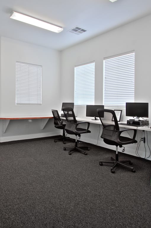 an office with three desks with chairs and a computer