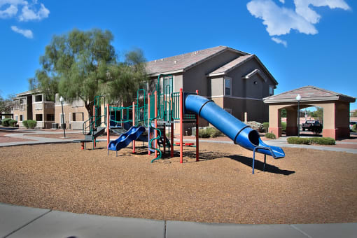 a playground with a blue slide in front of a building