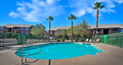 our resort style swimming pool is in front of our apartments with palm trees
