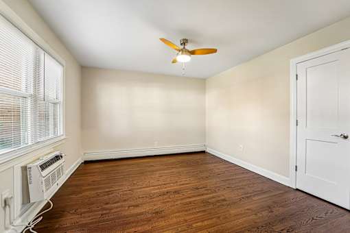 A room with a ceiling fan and a window with blinds.
