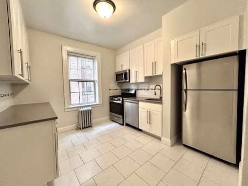 A kitchen with white cabinets and a stainless steel refrigerator.