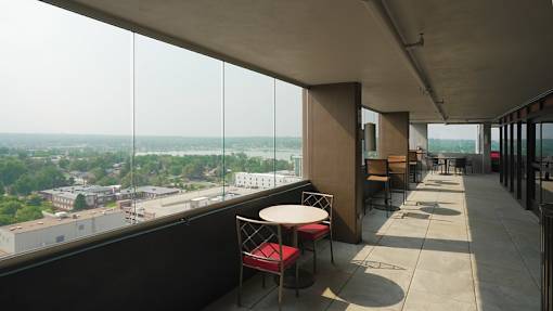 Enclosed exterior walkway with seating and Sloan's Lake in the distance at Denver Metro Village Apartments, Denver, CO, 80204