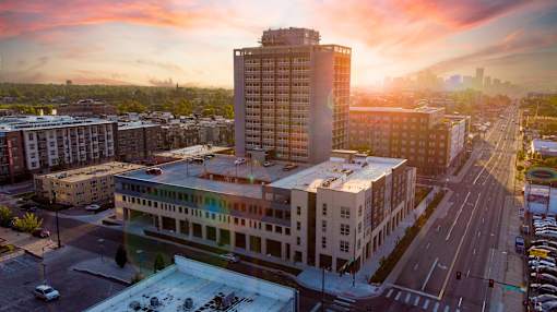 A cityscape with a large building in the foreground and a sunset in the background. at Denver Metro Village Apartments, Denver, CO