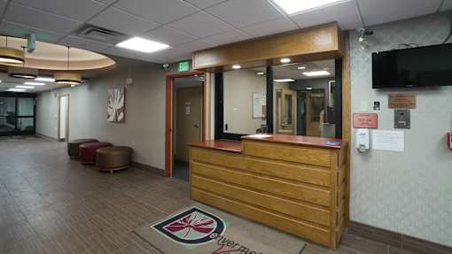 A reception area with a wooden desk and a rug with a compass design at Denver Metro Village Apartments, Colorado