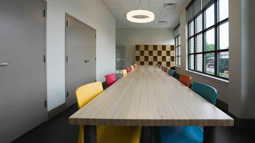 A long table with chairs around it in a room with a checkerboard patterned wall at Denver Metro Village Apartments, Colorado, 80204