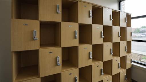 A series of wooden lockers with metal handles and a key slot at Denver Metro Village Apartments, Denver, CO
