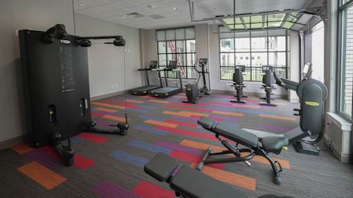 A gym with a variety of equipment including treadmills, weights, and exercise machines at Denver Metro Village Apartments, Denver, CO, 80204