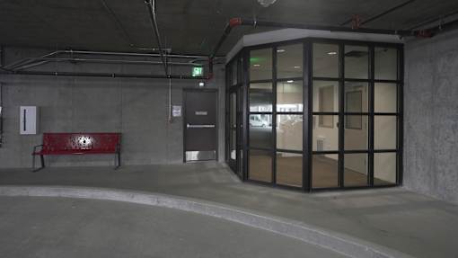 A red bench sits in a concrete room with a glass door at Denver Metro Village Apartments, Denver, Colorado